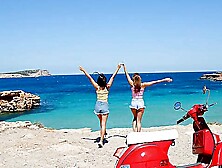 Two beautiful girls have fun on the beach with a guy,  showcasing sensual moves.