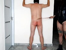 BDSM session. Dominatrix Nika spanked a slave on bare ass and whipped him on the back