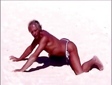 Suntanned man on beach in lil cable g-string temporarily