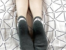 Girl With Long Legs Caresses Her Feet In Gray New Year Socks With Deer