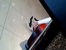 Asian stunner in sexy outfit dangling her candid heels at the shopping mall