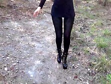 Walking on the wood wearing a ebony suit,  hose and high heels ankle boots