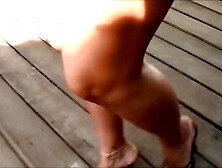 Tanned beauty shows her long legs and sexy feet while walking in her heels outside