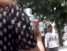 Cameraman hands her juice while she finds a spot to pee